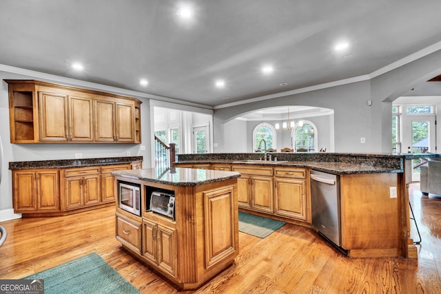 kitchen with stainless steel appliances, crown molding, a center island, and sink