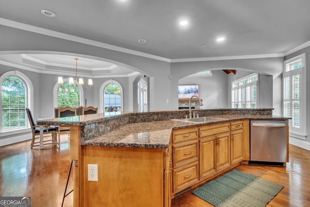 kitchen featuring a large island with sink, dishwasher, sink, and light hardwood / wood-style flooring