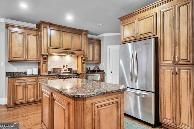 kitchen featuring dark stone countertops, stainless steel fridge, light hardwood / wood-style flooring, and a kitchen island