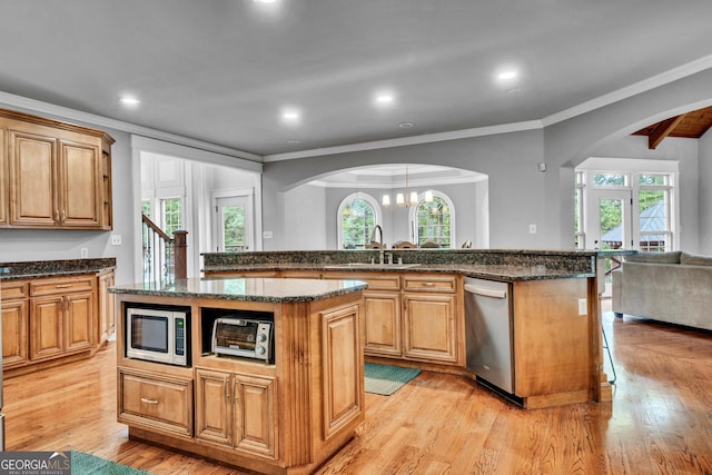 kitchen with a kitchen island, dark stone counters, light wood-type flooring, and appliances with stainless steel finishes