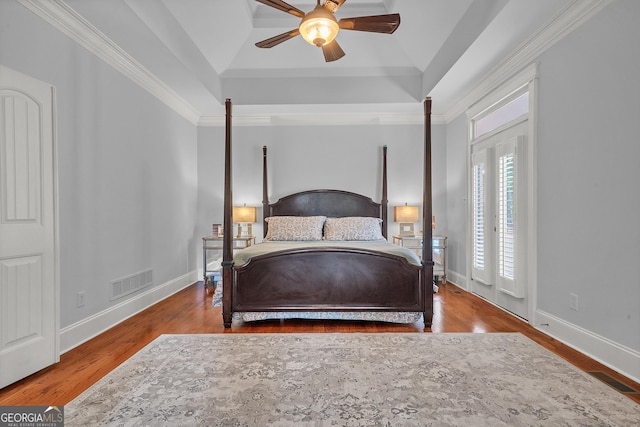 bedroom featuring hardwood / wood-style flooring, ceiling fan, a tray ceiling, ornamental molding, and vaulted ceiling