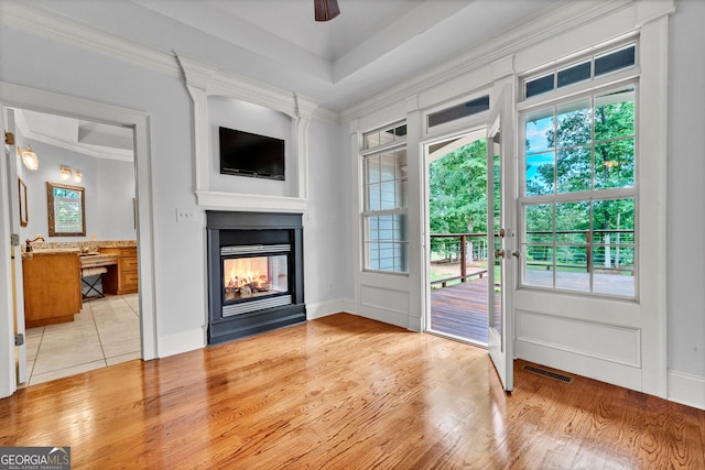 doorway featuring light hardwood / wood-style flooring, ornamental molding, ceiling fan, and a multi sided fireplace