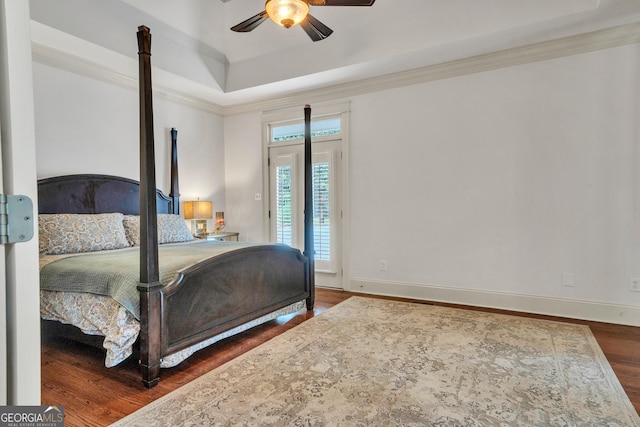 bedroom featuring dark hardwood / wood-style flooring, ornamental molding, ceiling fan, and a tray ceiling