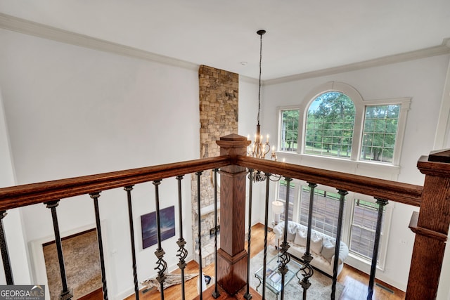 stairs with ornamental molding, hardwood / wood-style floors, and an inviting chandelier