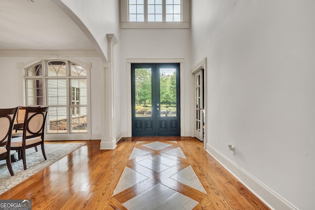 foyer entrance with french doors, ornamental molding, and light wood-type flooring