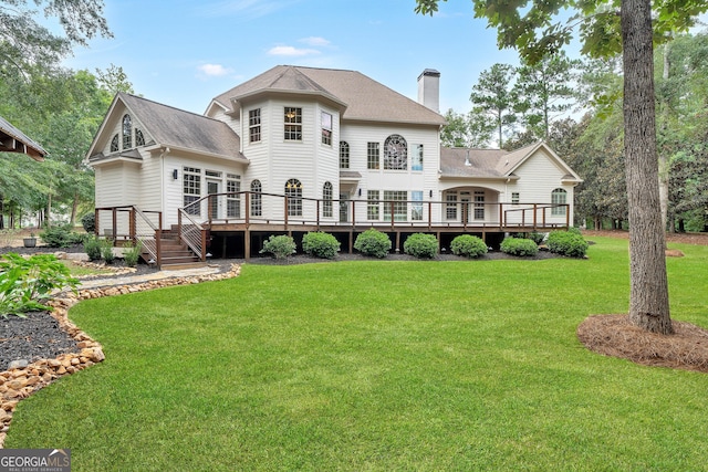 rear view of house with a wooden deck and a lawn