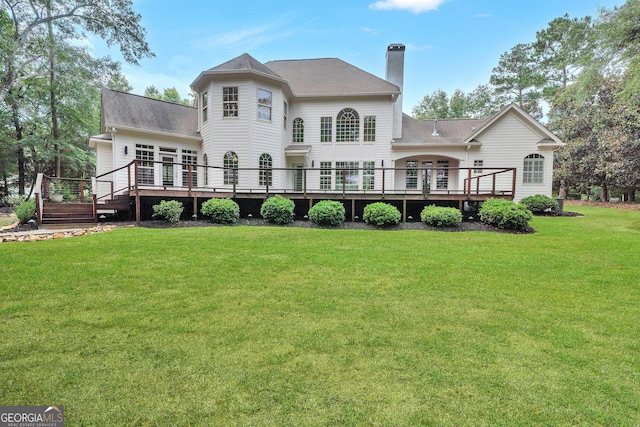 rear view of property with a wooden deck and a lawn