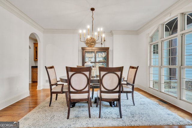 dining space with a notable chandelier, crown molding, and light hardwood / wood-style floors