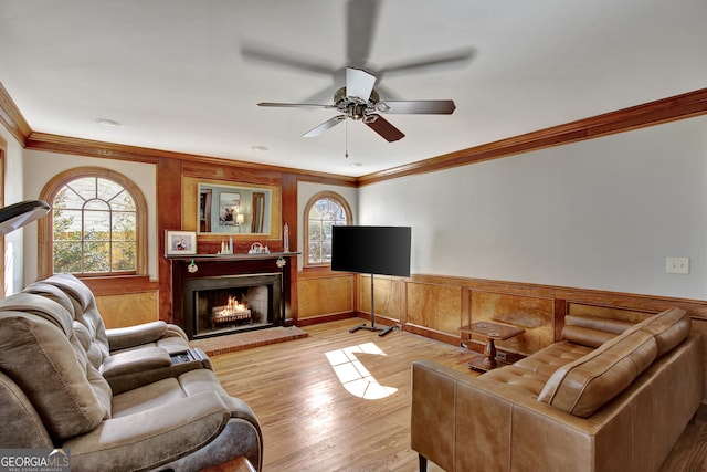 living room with crown molding, a healthy amount of sunlight, a fireplace, and light hardwood / wood-style floors