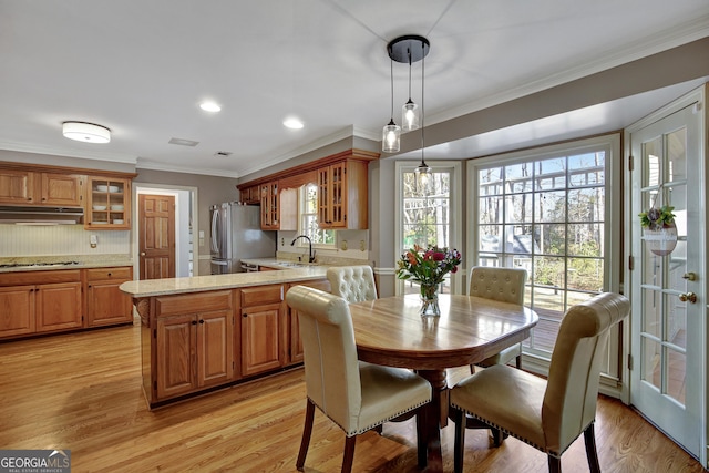 dining area with crown molding, sink, and light wood-type flooring