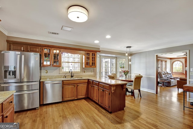 kitchen with sink, appliances with stainless steel finishes, hanging light fixtures, kitchen peninsula, and light wood-type flooring