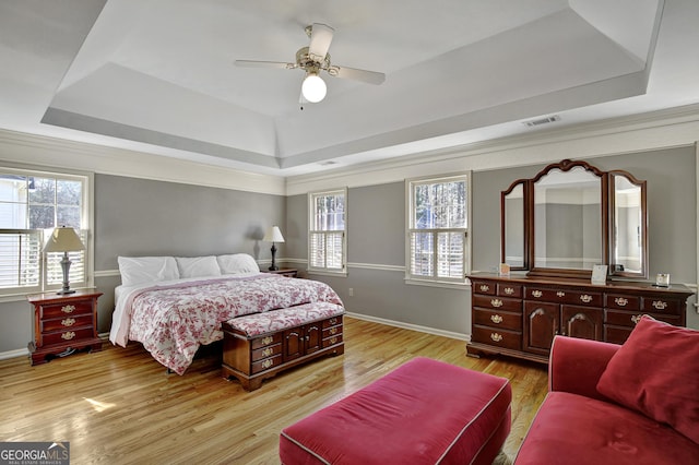 bedroom featuring ceiling fan, a raised ceiling, and light wood-type flooring