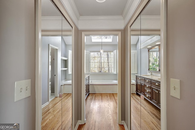 corridor featuring sink, crown molding, light hardwood / wood-style floors, and a healthy amount of sunlight