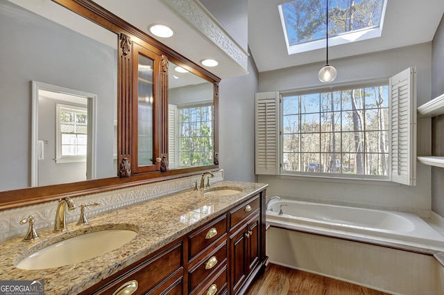 bathroom featuring a washtub, hardwood / wood-style floors, vanity, and a skylight