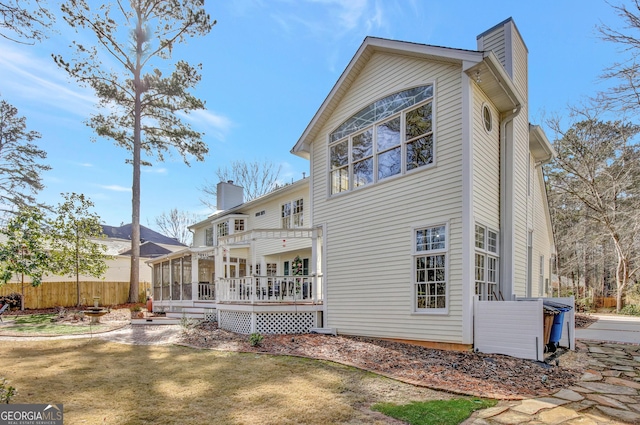 rear view of house featuring a wooden deck, a sunroom, and a lawn