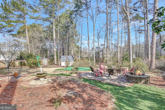 view of yard featuring a patio area, a storage unit, and an outdoor fire pit