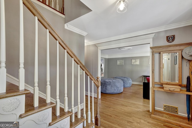 stairway featuring ornamental molding and hardwood / wood-style floors