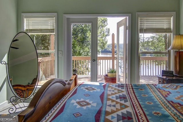 bedroom with multiple windows, access to exterior, and a water view