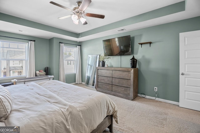 bedroom featuring light carpet, a raised ceiling, and ceiling fan