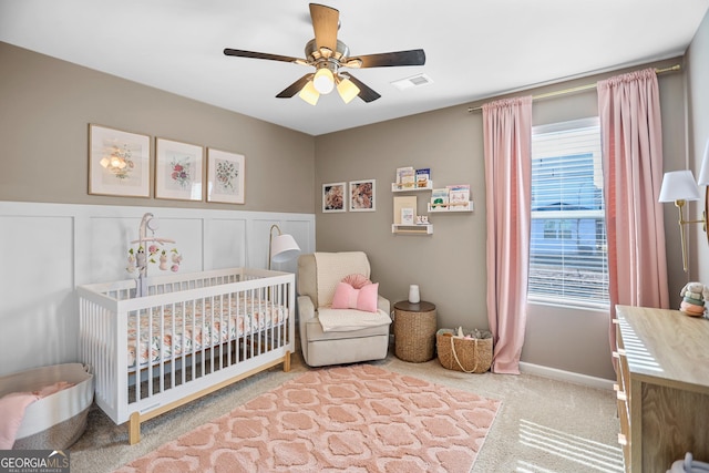 carpeted bedroom with a nursery area and ceiling fan