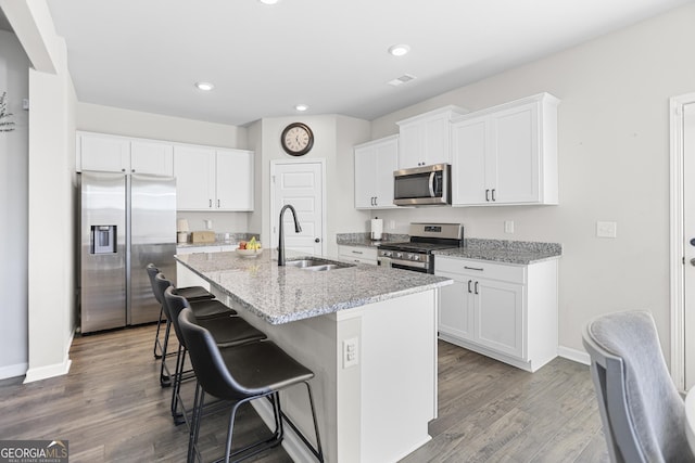 kitchen with a breakfast bar, sink, white cabinetry, a center island with sink, and stainless steel appliances