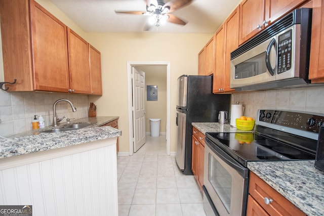 kitchen with sink, light tile patterned floors, stainless steel appliances, tasteful backsplash, and light stone countertops