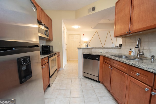 kitchen with stainless steel appliances, light stone countertops, sink, and light tile patterned floors