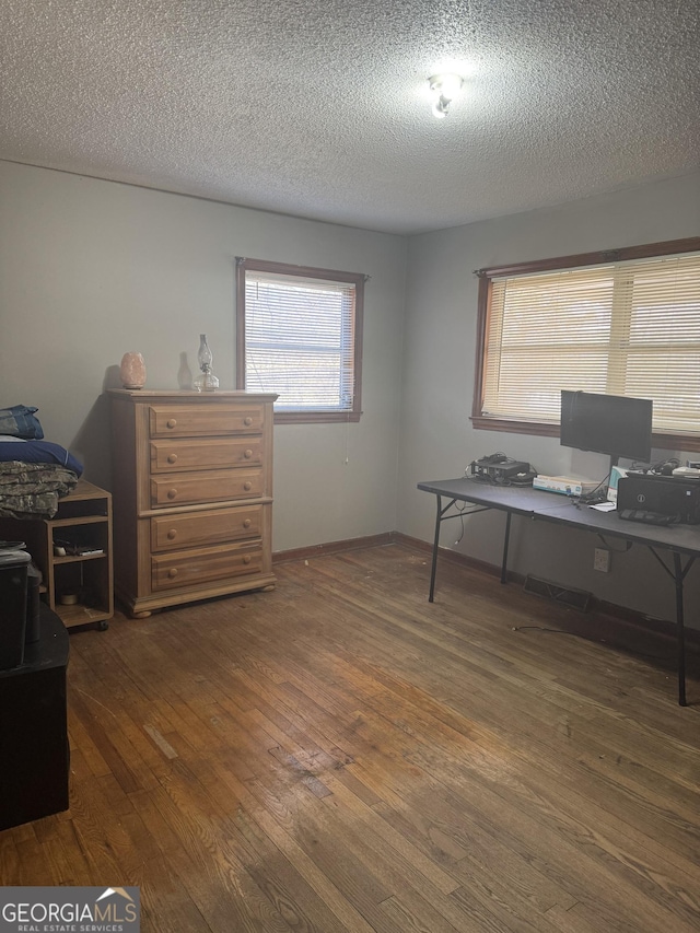 home office with dark wood-type flooring and a textured ceiling