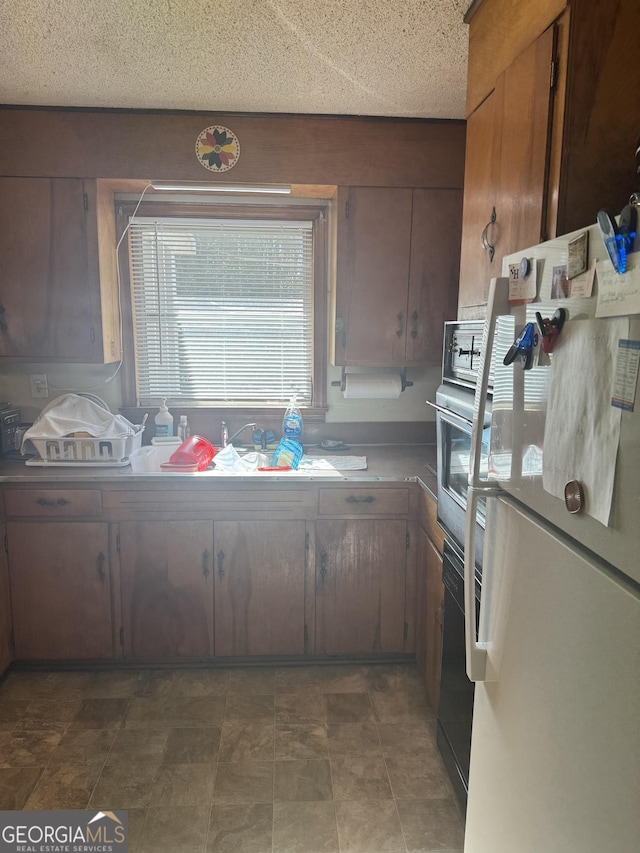 kitchen featuring white refrigerator, wall oven, and a textured ceiling