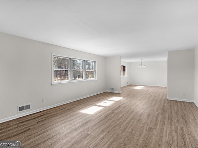 spare room with light wood-type flooring and an inviting chandelier