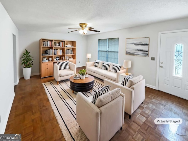 living room featuring ceiling fan, dark parquet flooring, and a textured ceiling