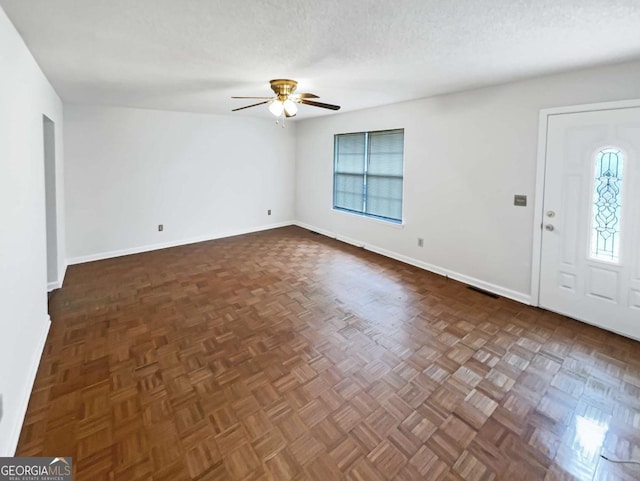 entryway with ceiling fan, plenty of natural light, dark parquet floors, and a textured ceiling