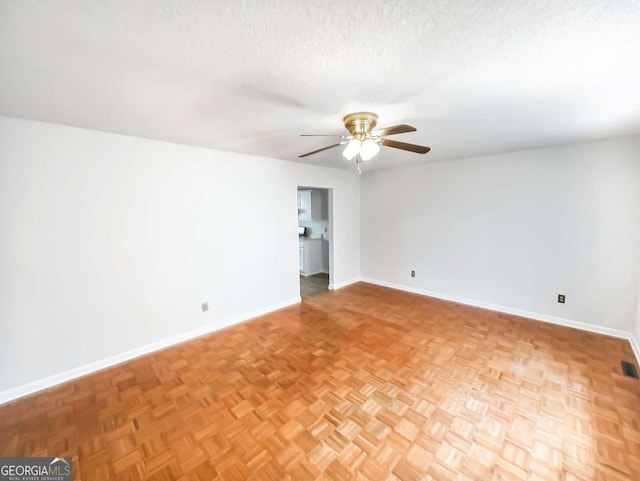 empty room featuring ceiling fan, light parquet flooring, and a textured ceiling