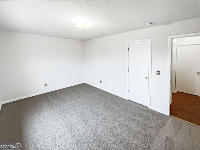 unfurnished bedroom featuring a textured ceiling and dark colored carpet