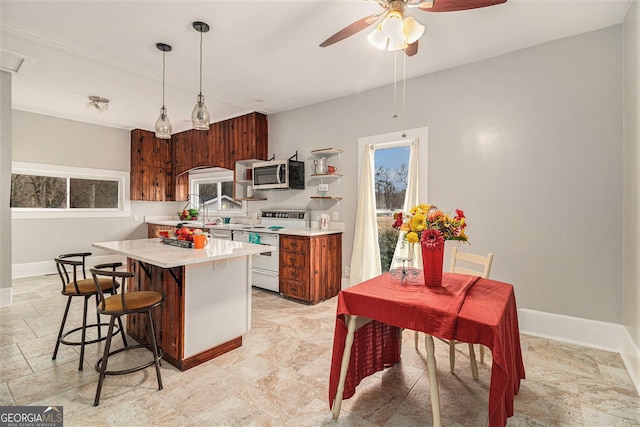 kitchen with ceiling fan, white electric range oven, decorative light fixtures, and a kitchen island