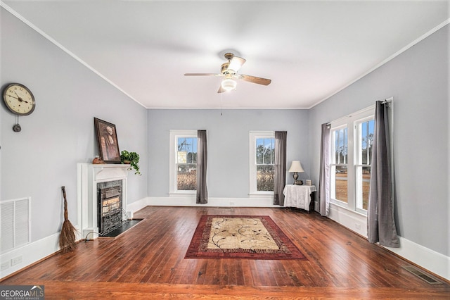 unfurnished living room featuring dark hardwood / wood-style flooring, ceiling fan, a fireplace, and a healthy amount of sunlight