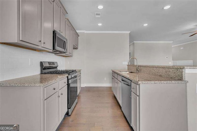 kitchen featuring sink, gray cabinets, appliances with stainless steel finishes, light stone countertops, and light wood-type flooring