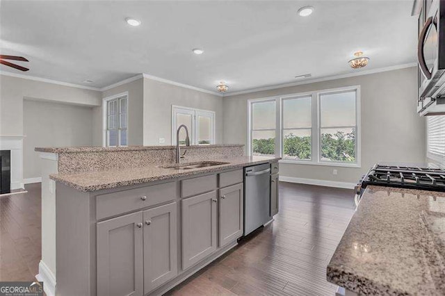 kitchen featuring sink, gray cabinetry, appliances with stainless steel finishes, an island with sink, and light stone countertops