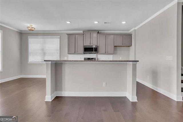 kitchen featuring light stone counters, ornamental molding, and gray cabinetry