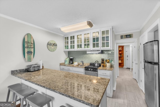 kitchen featuring stainless steel appliances, white cabinets, a kitchen bar, and kitchen peninsula