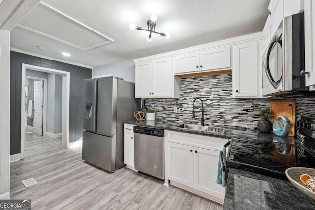 kitchen with sink, stainless steel appliances, dark stone counters, and white cabinets