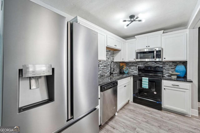 kitchen featuring appliances with stainless steel finishes, light hardwood / wood-style flooring, white cabinets, and decorative backsplash