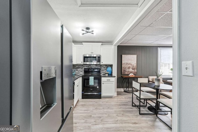 kitchen with white cabinetry, backsplash, electric range, and light hardwood / wood-style floors