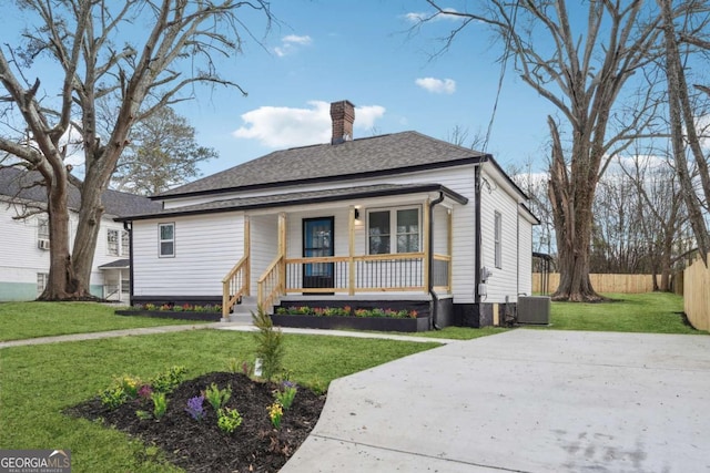 bungalow with a front lawn, central air condition unit, and covered porch