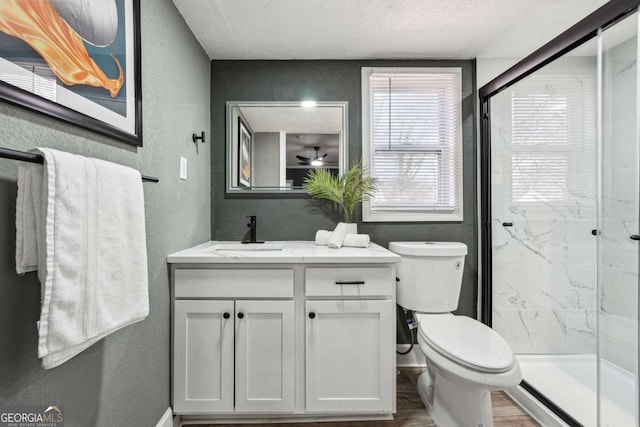 bathroom featuring walk in shower, vanity, toilet, and a textured ceiling