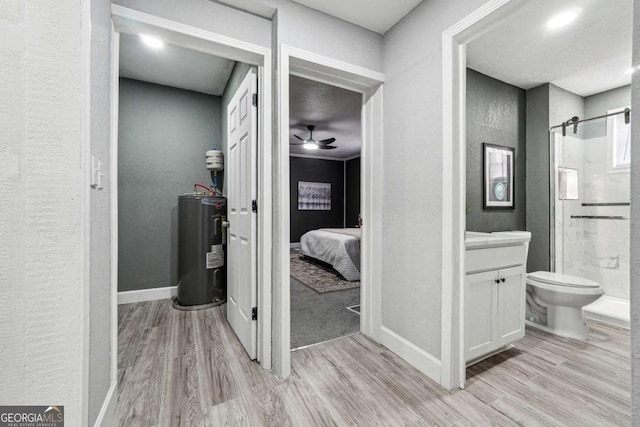 bathroom featuring wood-type flooring, vanity, an enclosed shower, ceiling fan, and electric water heater