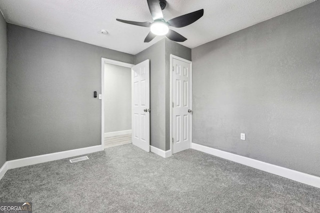 unfurnished bedroom featuring ceiling fan, carpet, and a textured ceiling