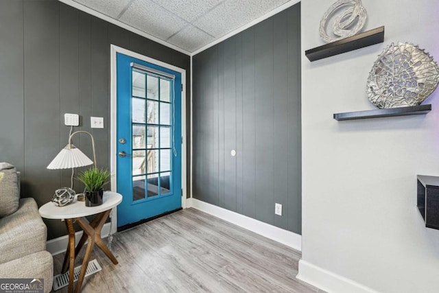 doorway to outside with hardwood / wood-style flooring, a drop ceiling, and wood walls