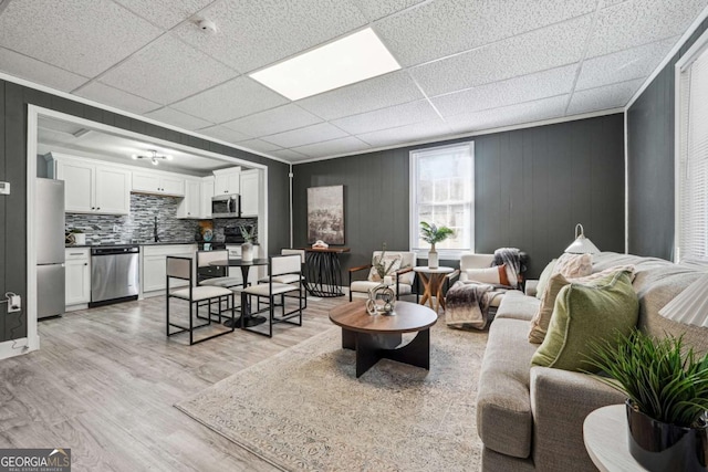 living room featuring sink, a paneled ceiling, and light hardwood / wood-style floors