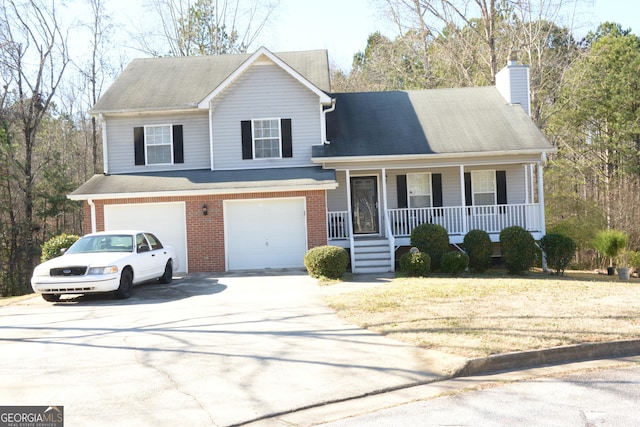 split level home with brick siding, a porch, a chimney, driveway, and an attached garage